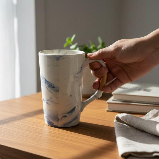 Premium pottery coffee mug, marbled blue white glaze, held by hand.