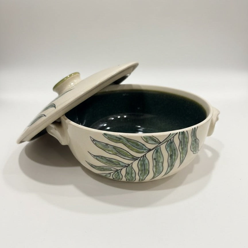 Leaf print ceramic casserole with lid and green botanical design on ivory base.